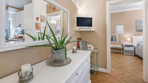 A well-lit bedroom with a TV, bedside table, lamp, and a bed. - Casa Amorosa Town Relax Alassio (Alassio)