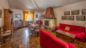 Un amplio espacio de sala con un sofá rojo, una mesa de comedor de madera y una chimenea.