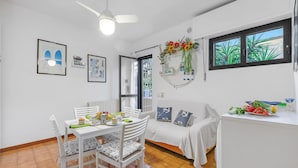 A bright dining area with a white table and chairs, a ceiling fan, and a window with a view of greenery. - Mare Sorriso 900m From Sea (Viareggio)