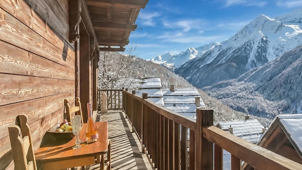 A wooden balcony with a table set for two, overlooking a snowy mountain landscape. - Baita Delle Stelle in Scarlino (Sauze di Cesana)