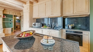 A modern kitchen with wooden cabinets, granite countertops, and a built-in oven. - Baita Delle Stelle in Scarlino (Sauze di Cesana)