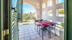 An open balcony with a table set for dining, a view of greenery, and a clear sky. - Family Village M6 Pool And Sea (Otranto)