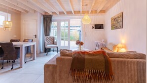 A cozy room with a dining table, a sofa, a TV, and a large window. - Holiday Home - Schoolstraat 6a Vrouwenpolder (Vrouwenpolder)