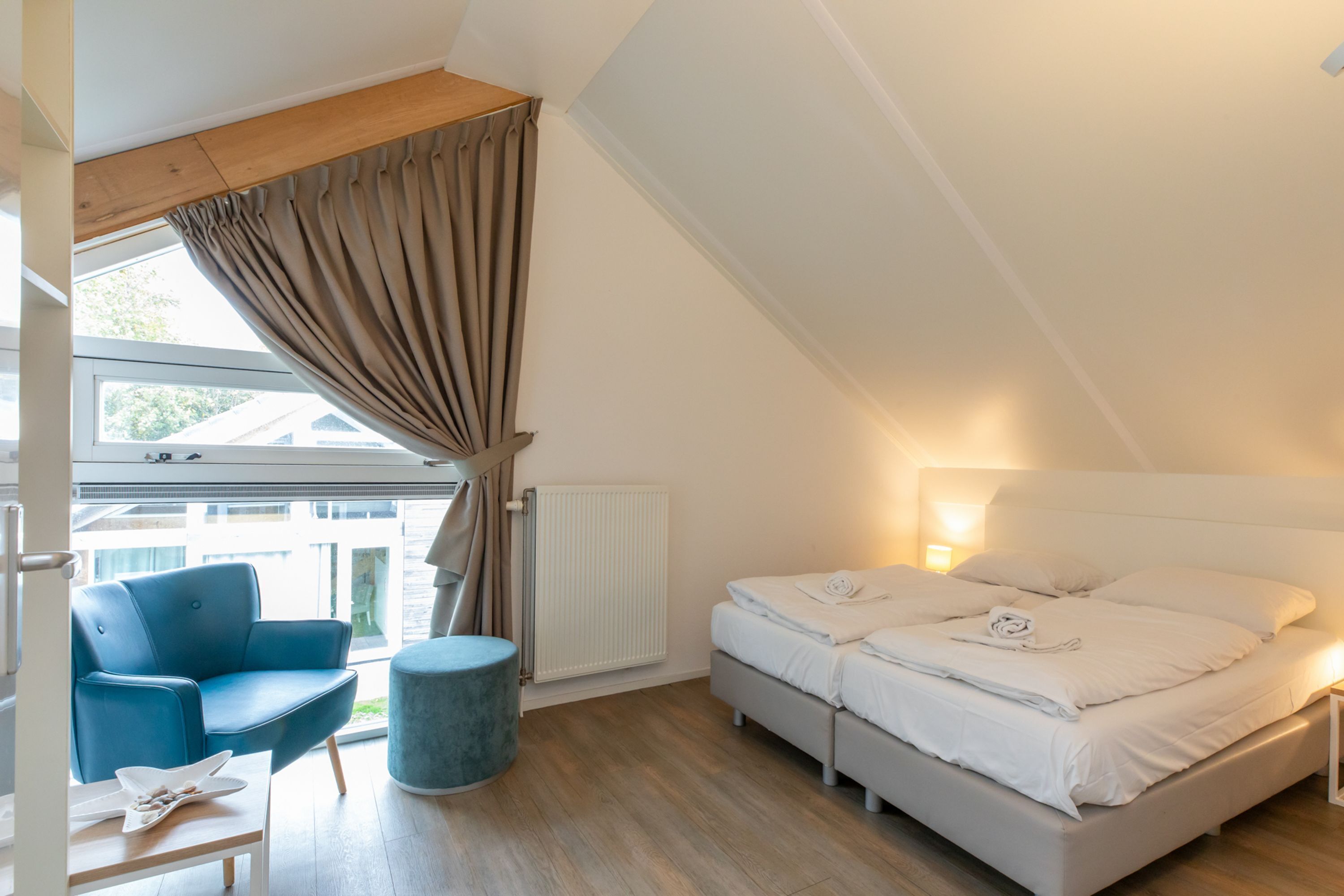 A bedroom with a bed, a chair, a table, and a window.