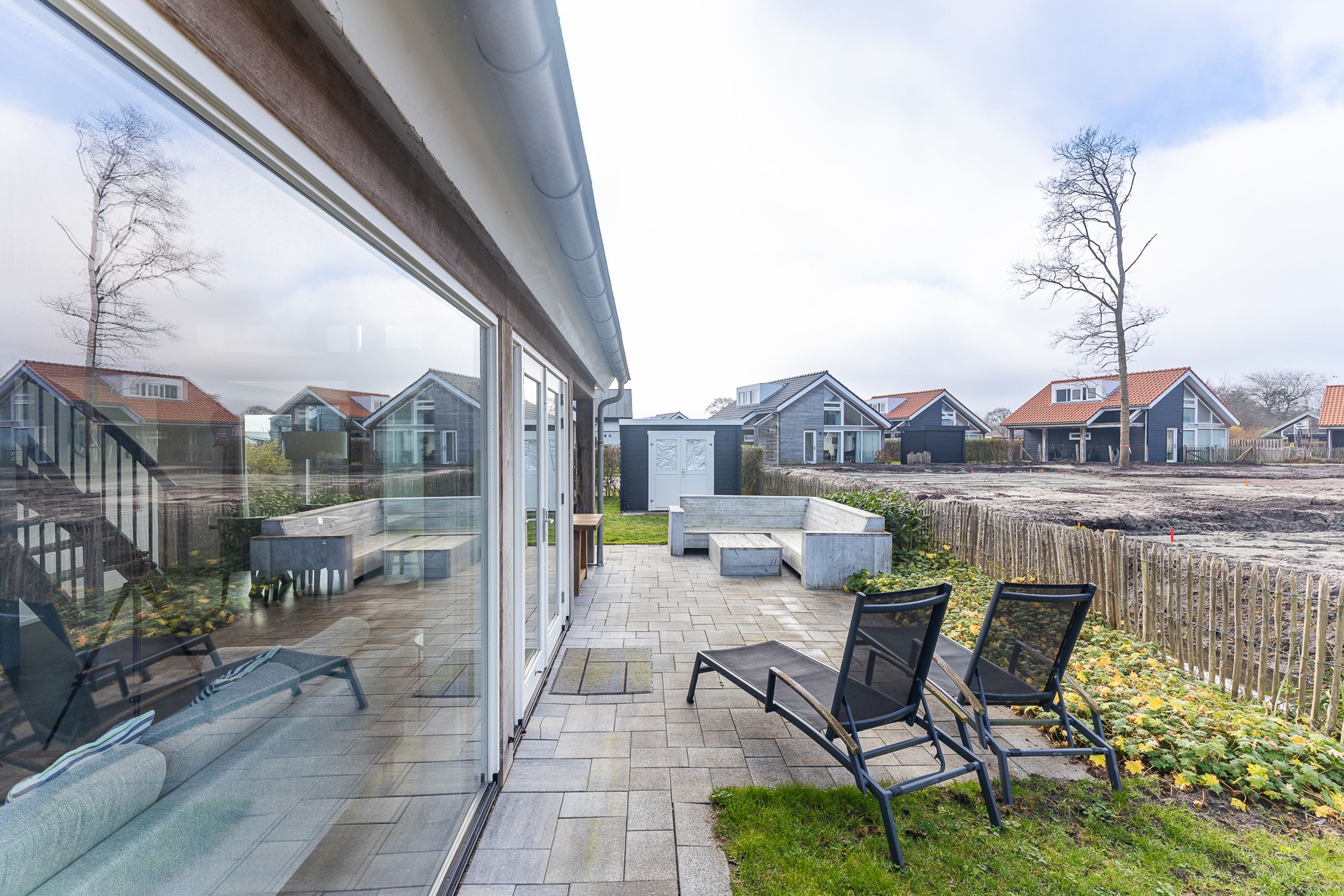 Eine moderne Terrasse mit Sitzgelegenheiten im Freien, Blick auf benachbarte Häuser und einen klaren Himmel.