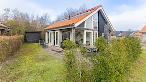 A modern house with a sloped roof, large windows, and a patio area. - Zonnedorp 1 Solskin Renesse Beach Holiday in Modern Holiday Home (Renesse)