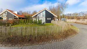A modern residential area with two houses, a paved driveway, and a wooden fence. - Zonnedorp 1 Solskin Renesse Beach Holiday in Modern Holiday Home (Renesse)