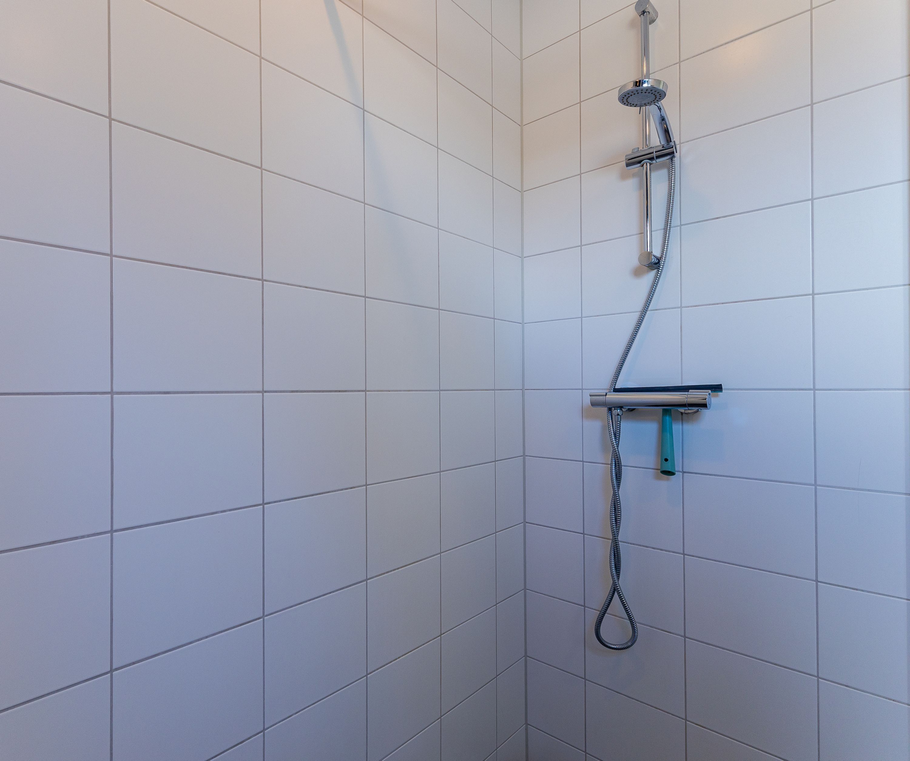 A shower with a handheld showerhead, a handheld shower attachment, and a flexible hose.