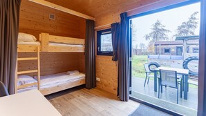 A wooden cabin with bunk beds, a dining area, and a view of a vehicle outside. - Duinhoeve Duinlodges 4pers Huisdiervriendelijk (Burgh-Haamstede)