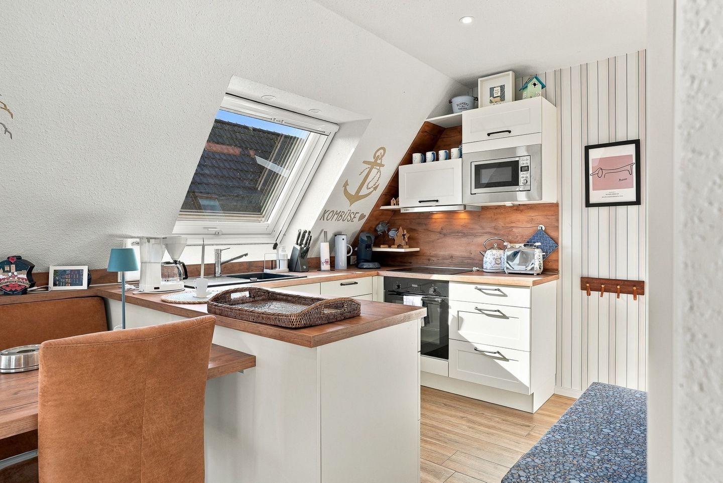 A compact kitchen with a built-in oven, microwave, and a window above the sink.
