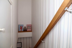 A staircase with a wooden handrail, a white door, and striped wallpaper. - Deichkrone - New Deichkrone vacation apartment with harbor view, balcony & (Krummhörn)