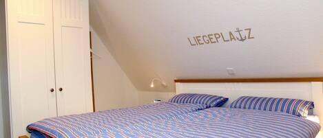 A bedroom with a bed, a wardrobe, and a wall with the text 'LIEGEPLATZ'.