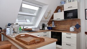 A compact kitchen with a skylight, white cabinetry, a Bosch microwave, and a wooden countertop. - Deichkrone - New Deichkrone vacation apartment with harbor view, balcony & (Krummhörn)