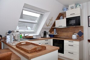 A compact kitchen with a skylight, white cabinetry, a Bosch microwave, and a wooden countertop. - Deichkrone - New Deichkrone vacation apartment with harbor view, balcony & (Krummhörn)