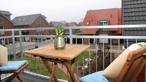 A balcony with a table, chairs, and a metal railing. - Deichkrone - New Deichkrone vacation apartment with harbor view, balcony & (Krummhörn)