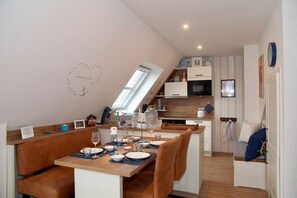 A compact kitchen with a dining area, a loft bedroom, and a small living space. - Deichkrone - New Deichkrone vacation apartment with harbor view, balcony & (Krummhörn)
