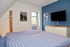 A bedroom with a bed, a TV, a window, and a wall-mounted picture. - Deichkrone - New Deichkrone vacation apartment with harbor view, balcony & (Krummhörn)
