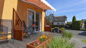 A wooden deck with outdoor furniture, a staircase, and a garden area with potted plants. - Cozy vacation apartment near the water - Ferienhaus Stark Apartment 01 - (Ralswiek)