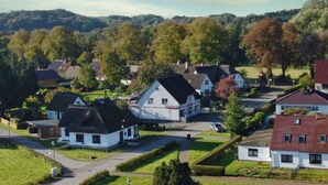 A residential area with houses, a central building with a sign, and a hilly background. - Cozy vacation apartment near the water - Ferienhaus Stark Apartment 01 - (Ralswiek)