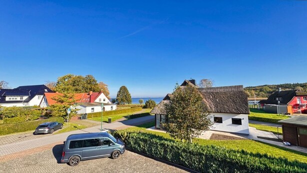 A residential area with a modern house, a parked car, and a thatched-roof structure. - Cozy vacation apartment near the water - Ferienhaus Stark Apartment 01 - (Ralswiek)