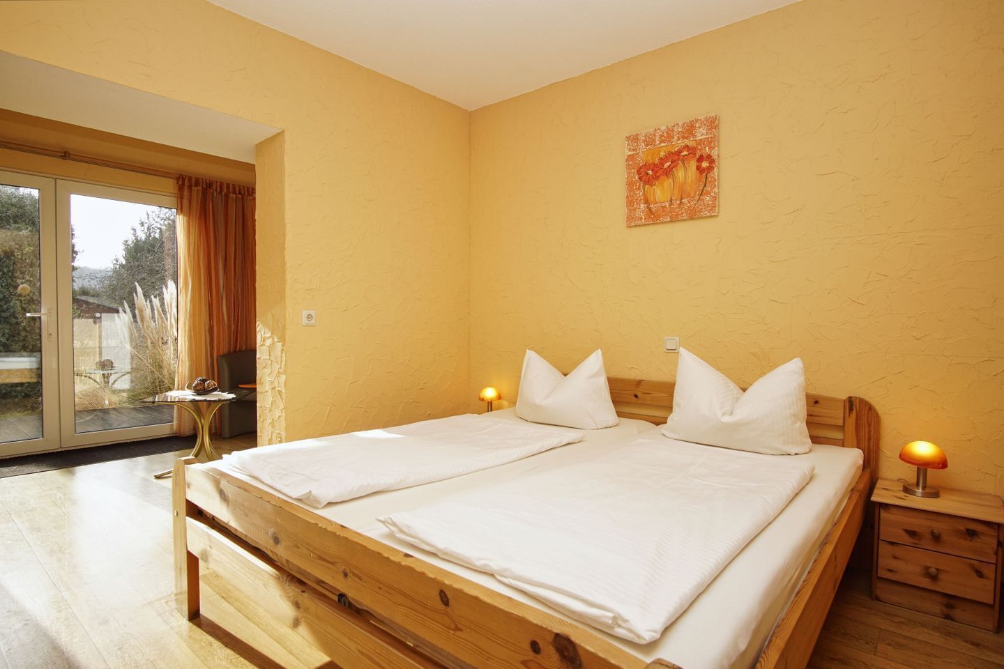 Un lit double avec du linge de lit blanc, une tête de lit en bois et deux tables de chevet avec des lampes.