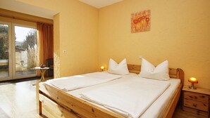 A double bed with white linens, a wooden headboard, and two bedside tables with lamps. - Cozy vacation apartment near the water - Ferienhaus Stark Apartment 01 - (Ralswiek)