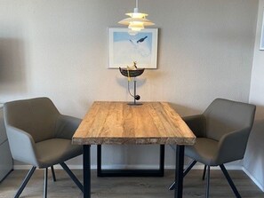 Une table à manger avec deux chaises, un luminaire suspendu et un tableau encadré au mur.