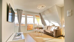 Een moderne woonkamer met een bank, salontafel en een aan de muur bevestigde televisie.