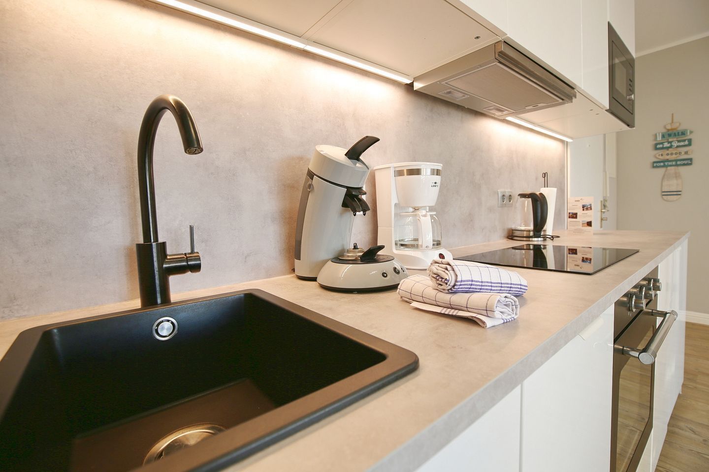 A modern kitchen with a black sink, a coffee maker, and a towel on the counter.