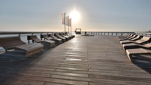 Een houten terras met banken en een leuning, met uitzicht op een waterpartij.