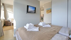Een moderne hotelkamer met een bed, een televisie, een bank en een badkamer die door een open deur zichtbaar is.