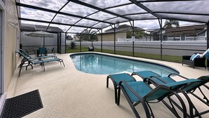 Un espace piscine extérieur doté d’un patio couvert, de chaises longues et offrant une vue sur les maisons voisines.