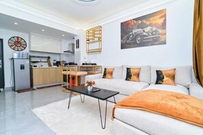 Ein modernes Wohnzimmer mit einer Couch, einem Couchtisch und einer Küche im Hintergrund.