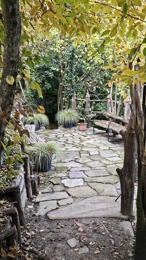 Un sendero de piedra que atraviesa un jardín con plantas en macetas y estructuras de madera.