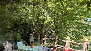 A stone patio with a table and chairs, surrounded by lush greenery and potted plants. - Casa del Falco - Borgo Spigone - Vetto d'Enza - Reggio Emilia (vetto)
