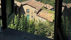 A rustic stone building with a tiled roof, surrounded by lush greenery and hills in the background. - Casa del Falco - Borgo Spigone - Vetto d'Enza - Reggio Emilia (vetto)