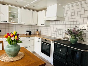 A modern kitchen with white cabinets, a black oven, and a wooden countertop.