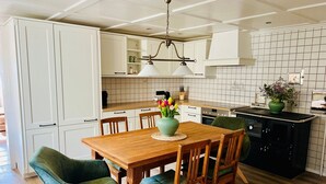 A modern kitchen with white cabinets, a wooden dining table, and green upholstered chairs. - Holiday Apartment 'Heimatnest' with Lovely View, Private Terrace & Shared Garden (Ibach)