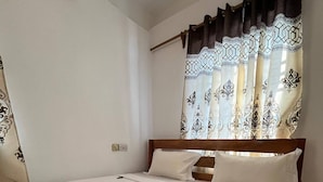 A neatly made bed with white linens, a woven basket with towels, and a red flower on the bed. - Cozy 3-bedroom Home 2 Minutes From Jambiani Beach (Jambiani)