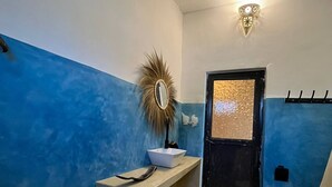 A bathroom with a blue and white color scheme, a sink with a mirror, a toilet, and a wall-mounted light fixture. - Cozy 3-bedroom Home 2 Minutes From Jambiani Beach (Jambiani)