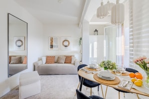 A modern living room with a sofa, a dining table set for four, and a large mirror. - Bright Panoramic Penthouse with Stunning Wrap-Around Terrace (Lucca)