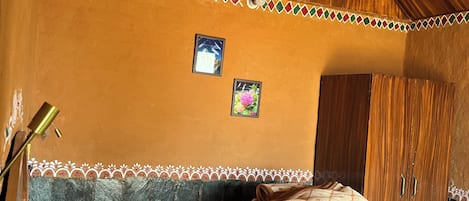 Un dormitorio con techo inclinado, una cama con ropa de cama estampada, un armario y dos cuadros en la pared.