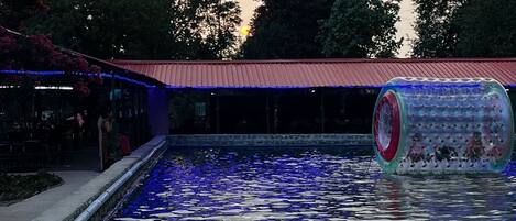 A swimming pool with a water slide and a covered area with seating.