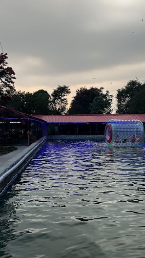 A swimming pool with a water slide and a covered area with seating.