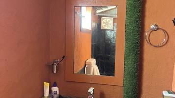 Un baño con lavamanos blanco, espejo y retrete.