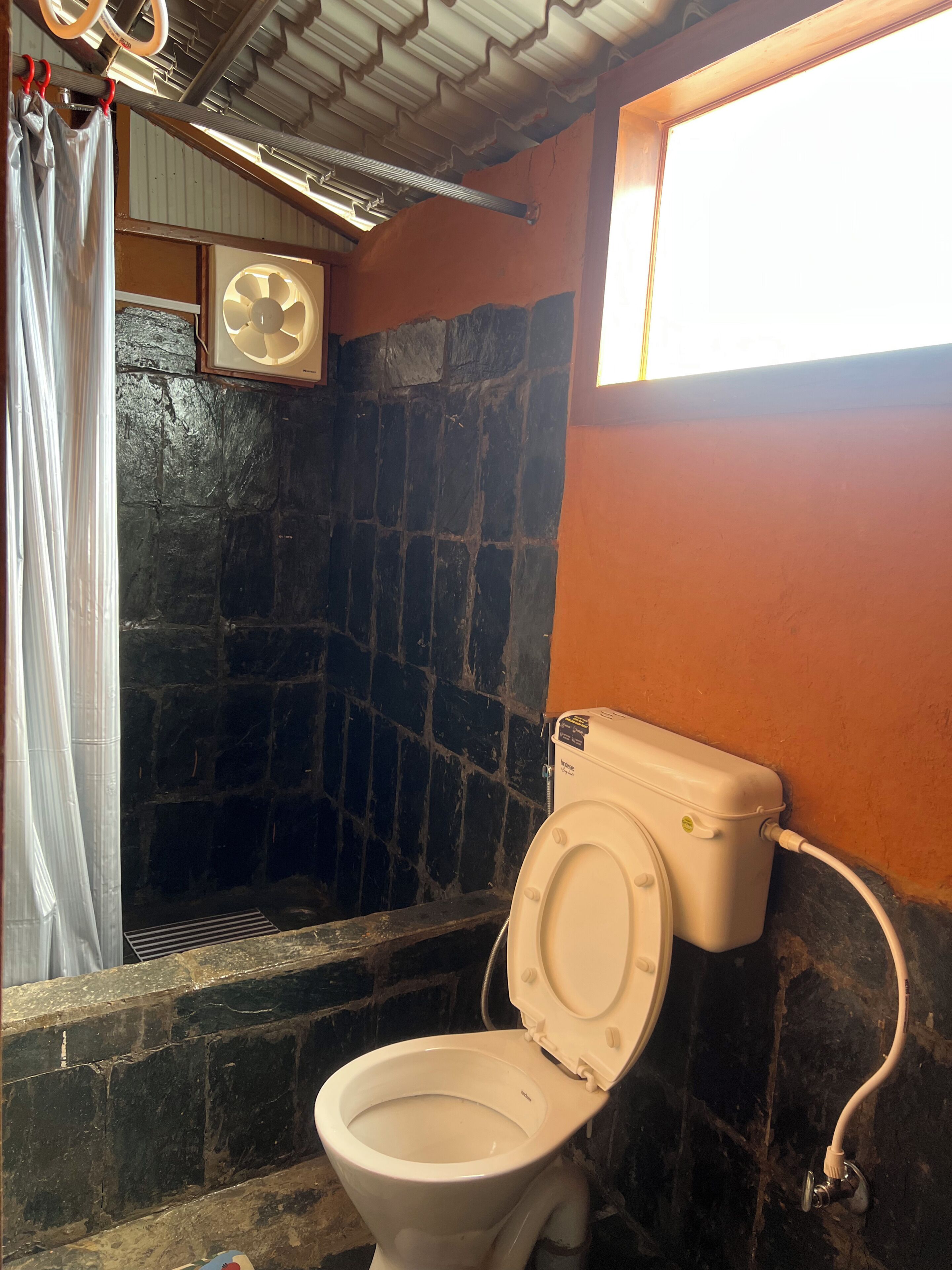 A bathroom with a toilet, a shower, and a window.