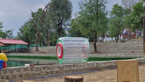 A park with wooden benches and a large green and red sculpture. - Mhara Himachal (Bir)