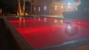 En modern byggnad med en pool som är upplyst på natten.