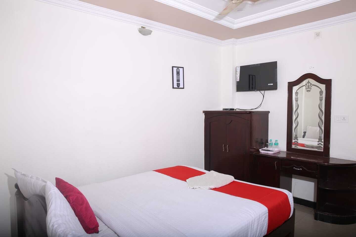 Una habitación de hotel con cama, cómoda, espejo y televisor.