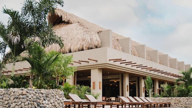 A resort with a pool area, lounge chairs, and a thatched-roof building. - Naio Hotel (Dibulla)